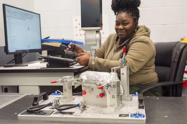 An employee operating a piece of quality assurance equipment to confirm the part geometry meet specifications An employee operating a piece of quality assurance equipment to confirm the part geometry meet specifications