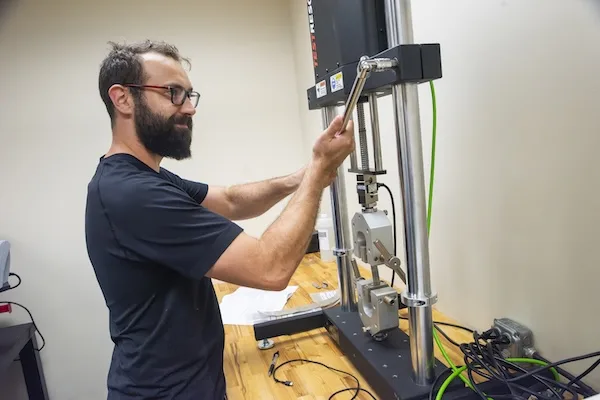 An employee loosening a bolt on a tensile testing machine with a socket wrench An employee loosening a bolt on a tensile testing machine with a socket wrench