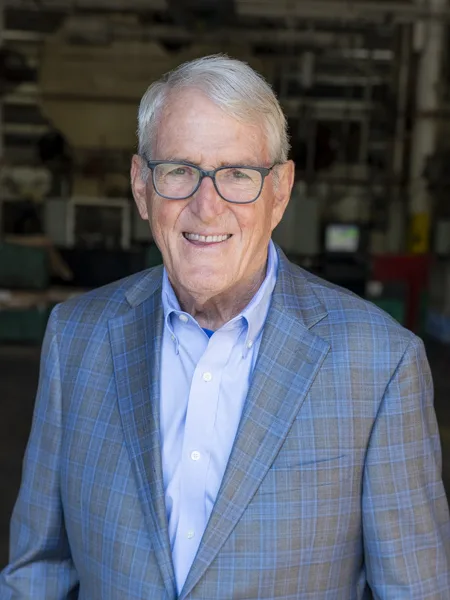 Dan T Moore III - Chairman of the Board and Founder Soundwich Founder and Chairman of the Board Dan T Moore III. Dan has short white hair and is wearing a light blue button-down shirt, a blue and grey plaid jacket, and eyeglasses.